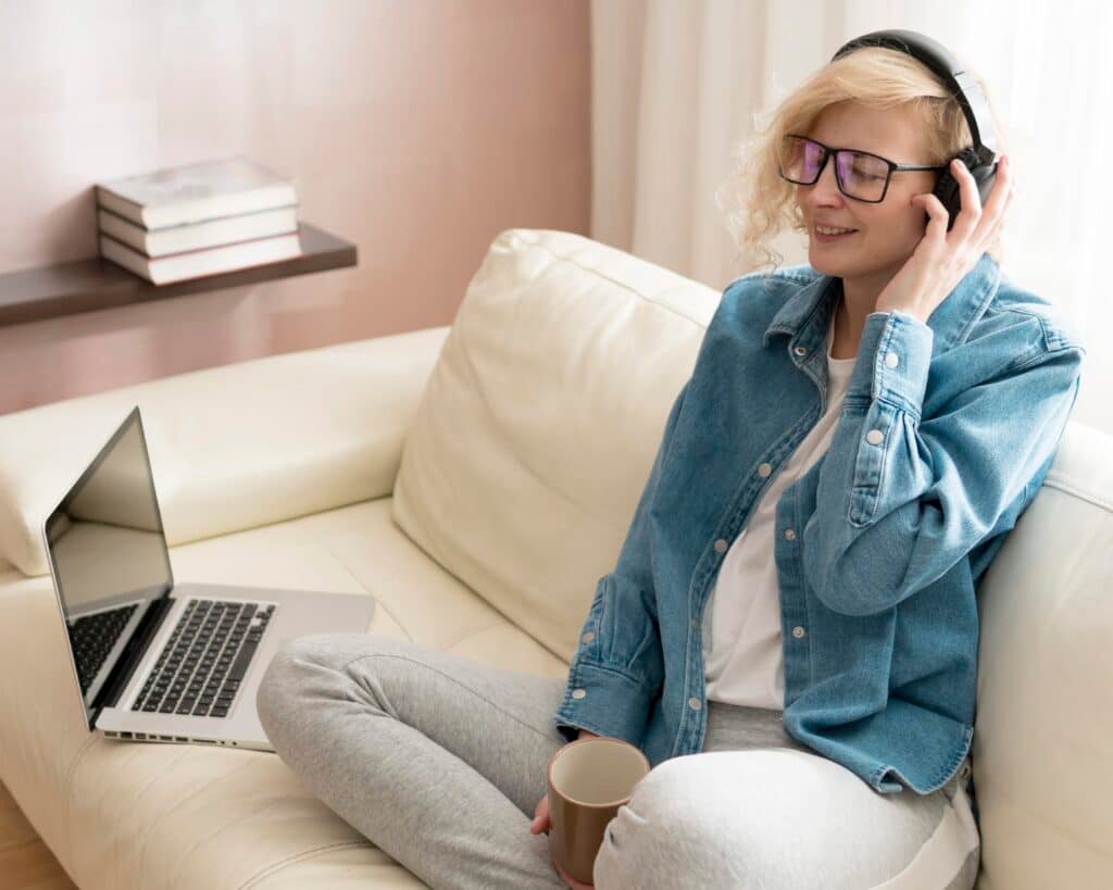 woman listening music holding coffee mug couch